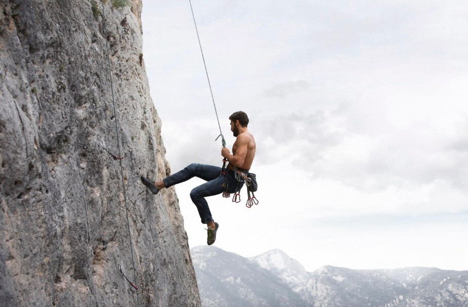 Man rock climbing on a steep mountain wall, representing the adventurous travel style for thrill-seeking personalities.