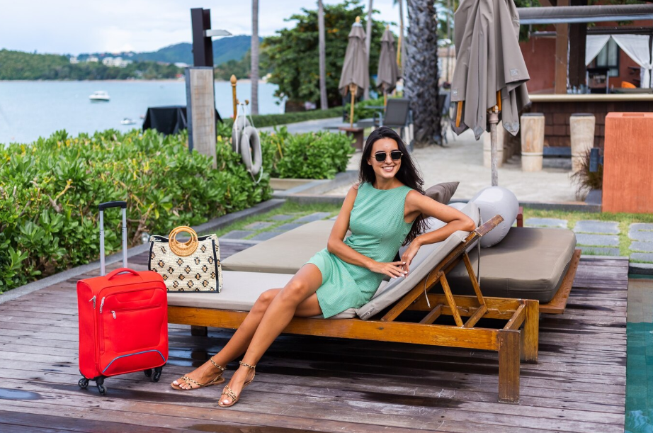 Woman relaxing at a luxury resort with luggage, representing the luxurious travel style for comfort-seeking personalities.