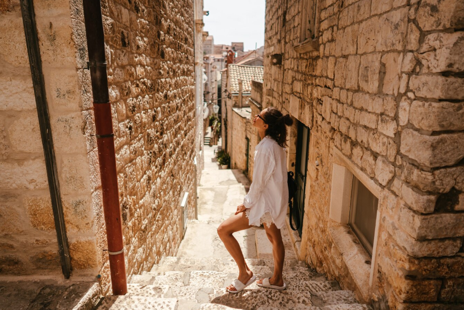 Woman exploring a historic stone alley in Europe, representing the culture-seeking travel style for curious travelers.