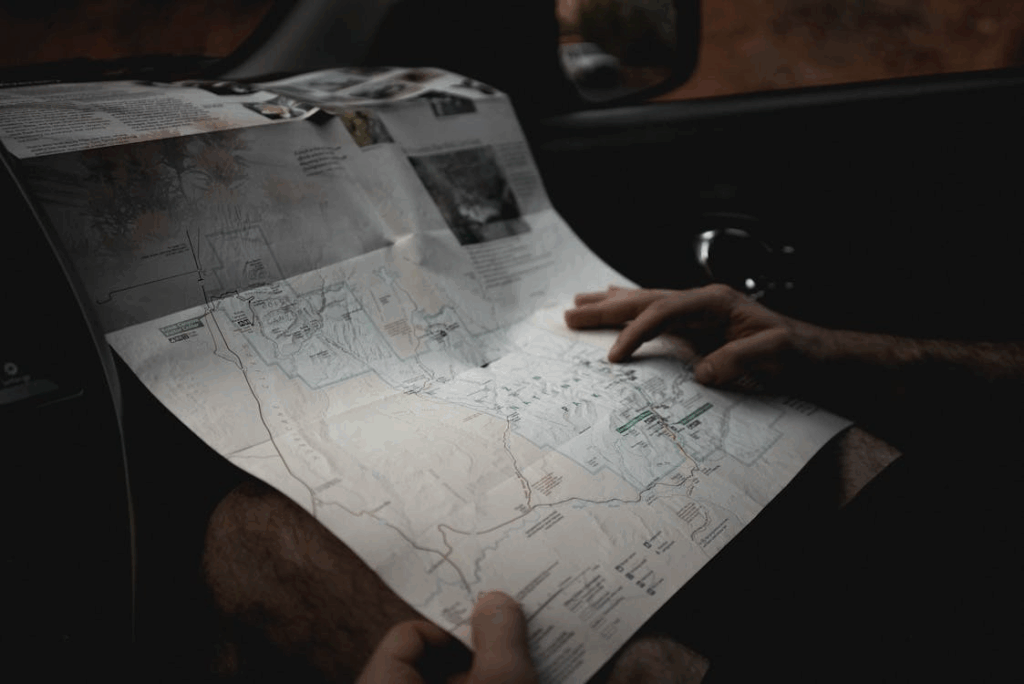 Traveler reading a road map inside a car and planning a long weekend getaway with a simple travel itinerary.