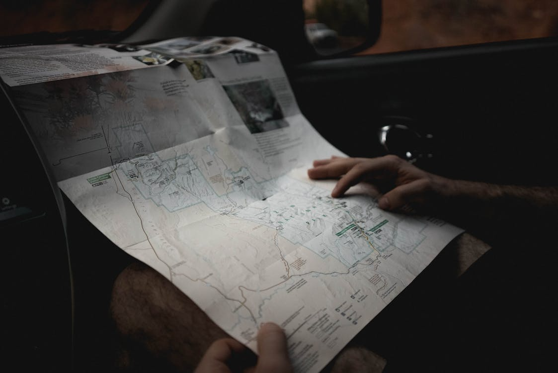 Traveler reading a road map inside a car and planning a long weekend getaway with a simple travel itinerary.