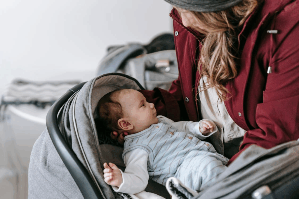 Mother comforting baby in a travel stroller while preparing for a trip.