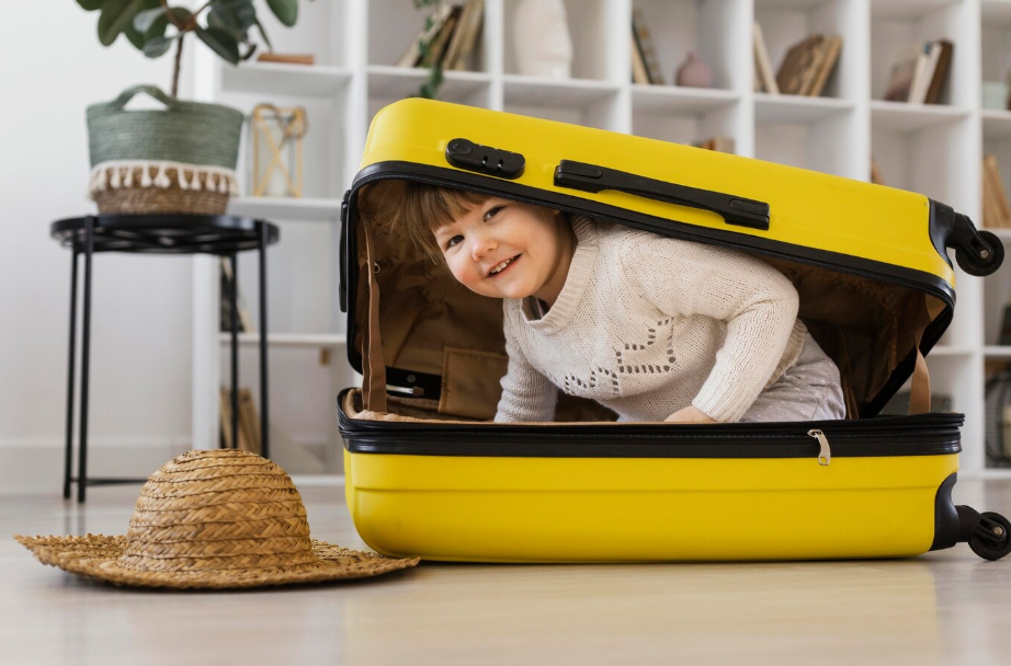 Smiling preschooler playing inside a yellow suitcase, fun travel moment highlighting packing tips for kids.