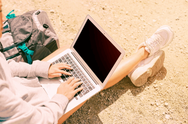 Digital nomad working remotely from beachside café with laptop and coffee