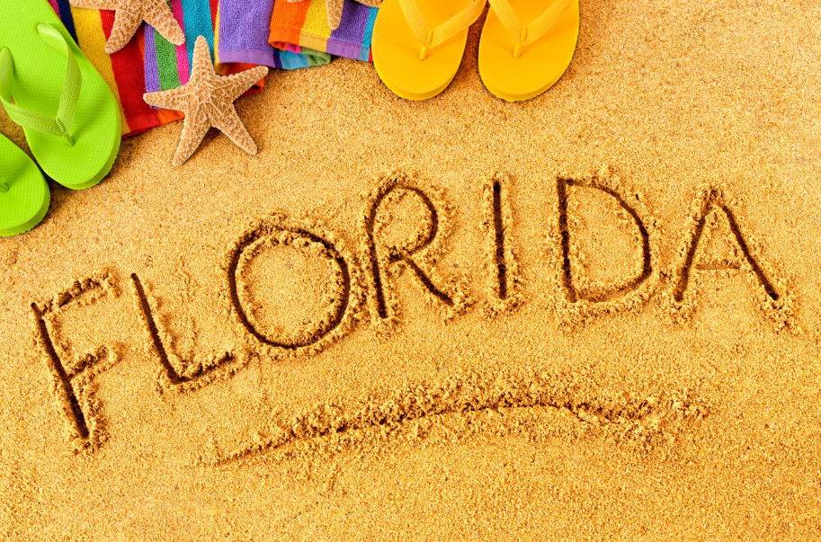 Florida vacation concept with flip-flops, starfish, towels, and 'Florida' written in the sand