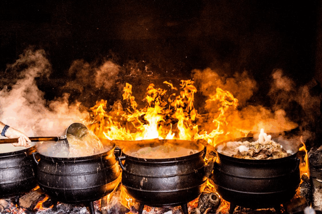 Traditional Portuguese cooking over open fire with boiling iron pots and local ingredients
