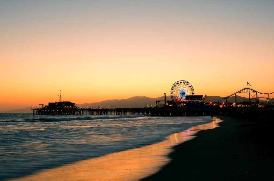 Santa Monica Pier at sunset with the Ferris wheel lit up, a must-see stop on a California coastal road trip.