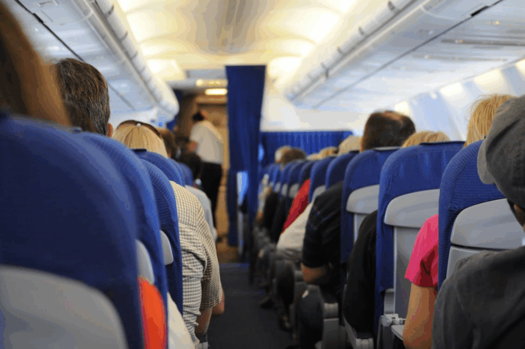 Passengers seated in economy class cabin on a commercial flight, illustrating typical budget airline seating layout