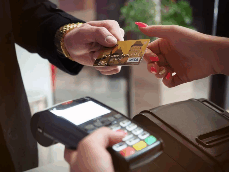 Customer handing over a gold Visa travel credit card for payment