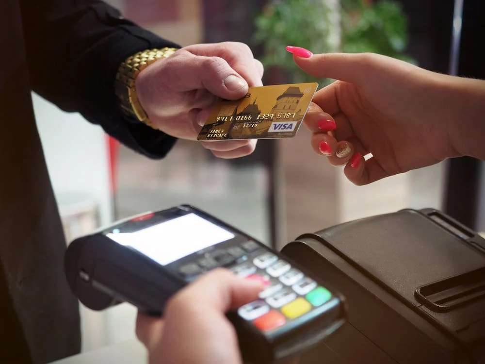 Customer handing over a gold Visa travel credit card for payment