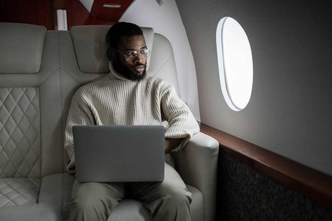 Passenger working on laptop in first class seat on airplane