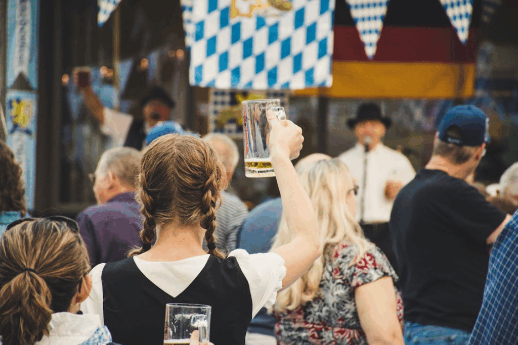 Woman raising a beer stein at Oktoberfest celebration with traditional Bavarian decor and live German music.