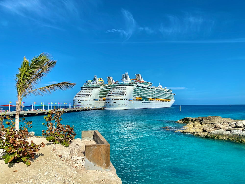 Cruise ships docked at a Caribbean port with turquoise water and clear skies