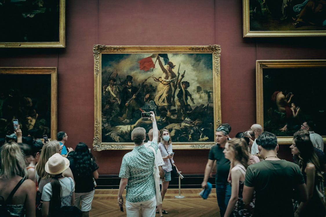 Visitors viewing paintings in the Louvre Museum in Paris, one of the best cities for art lovers.