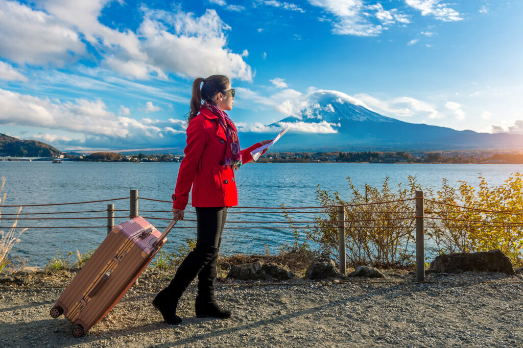 First-time international traveler in Japan with a suitcase near Mount Fuji.